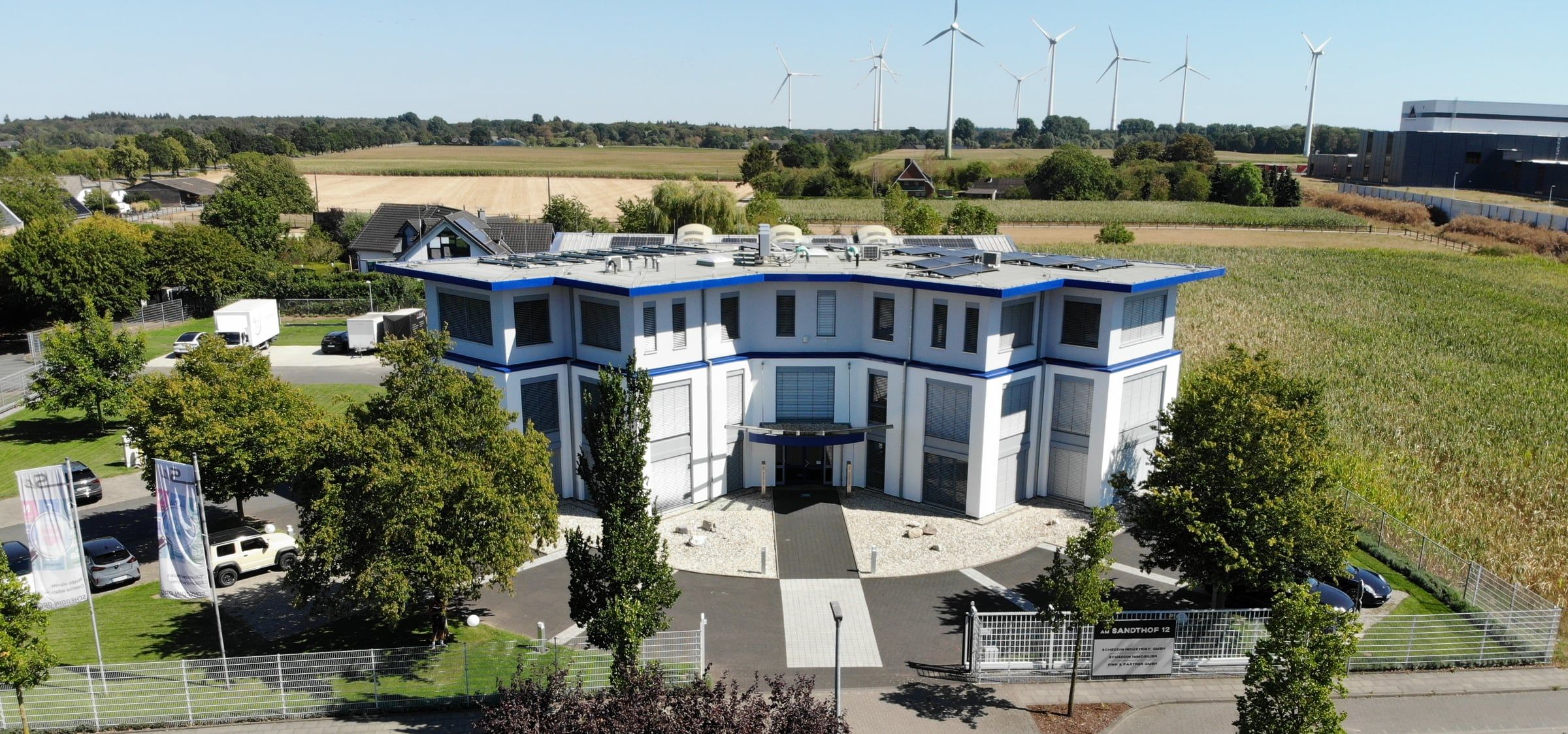 Firmengebäude von Fink & Partner am Sandthof in Goch aus der Luft, im Hintergrund Felder und Windräder