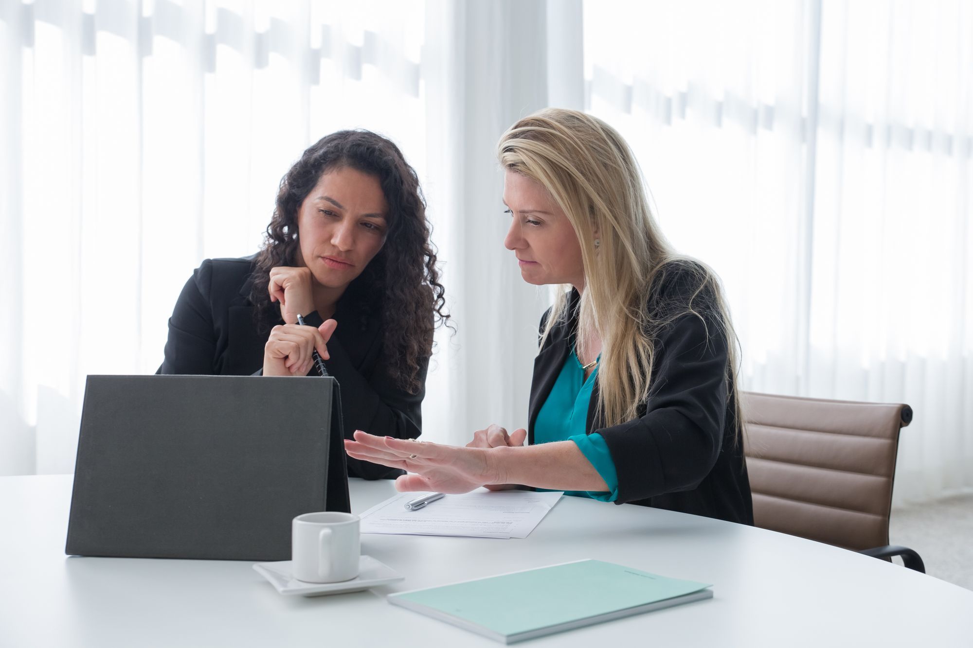 Zwei Frauen besprechen sich an einem Tisch mit Laptop